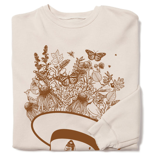 Heather dust sweatshirt with a brown graphic of a National Park Service hat overflowing with wildflowers, butterflies, and birds.