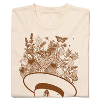 A folded natural colored shirt with brown ink depicting an upside down park ranger hat with flowers, leaves, birds, and pollinators emerging from it.