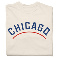 Folded ivory heavyweight t-shirt with "CHICAGO" printed in curved blue font. A red arch is printed below the text, parallel to it.