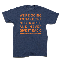 A heather denim tee with orange ink print that says, "We're going to take the NFC North and never give it back. Ryan Poles, January 2022"