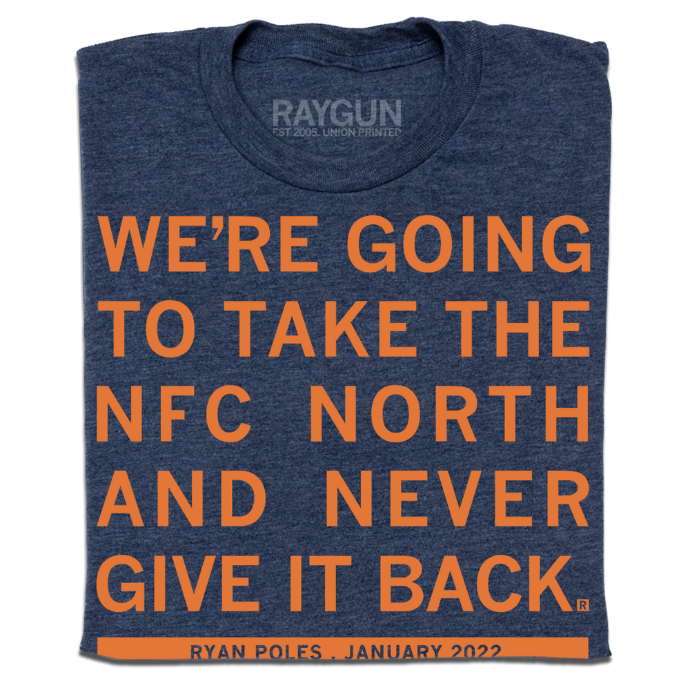 a folded heather navy t-shirt with orange ink text that reads "We're going to take the NFC North and never give it back"