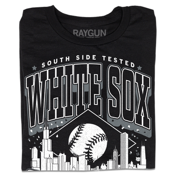 A folded black t-shirt with white ink. Text reads "South Side tested. White Sox Chicago. Pope approved." with the Chicago skyline in the center and a baseball above it.