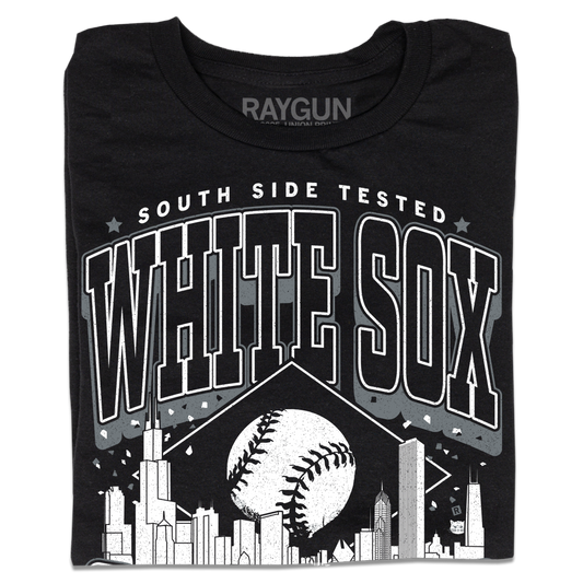 A folded black t-shirt with white ink. Text reads "South Side tested. White Sox Chicago. Pope approved." with the Chicago skyline in the center and a baseball above it.