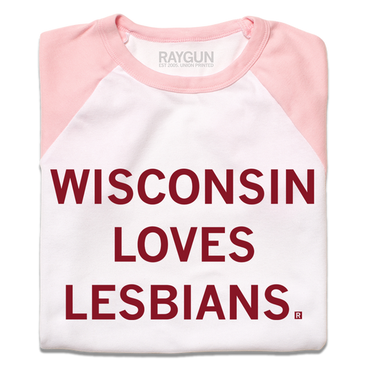 A folded white and pink baby tee with cardinal ink that says, "Wisconsin Loves Lesbians."