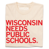 Cream-colored t-shirt featuring the red text WISCONSIN NEEDS PUBLIC SCHOOLS, a design that supports public education.