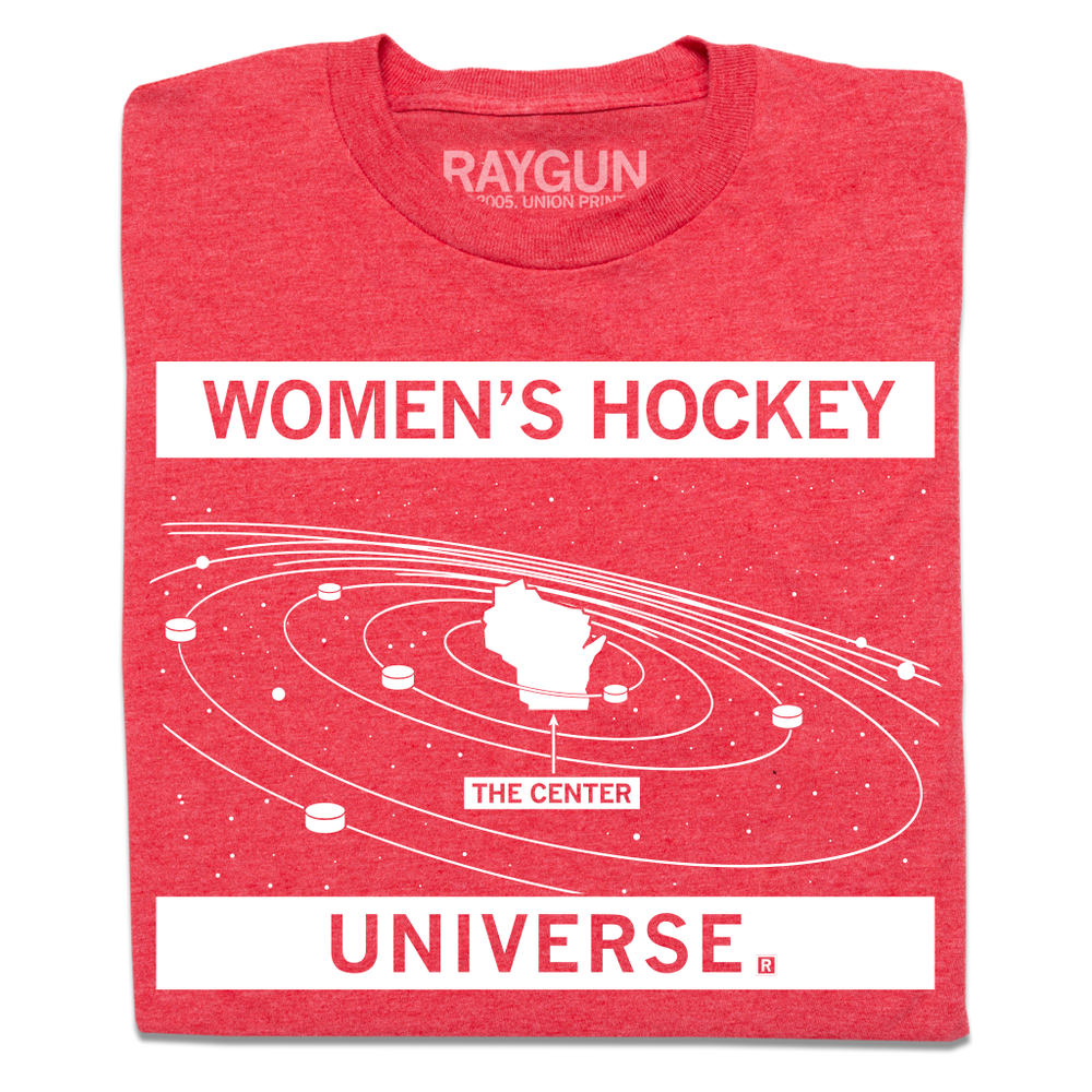 A folded heather red t-shirt with white ink. Text at the top says, "women's hockey" and at the bottom reads "universe." In between is the state of Wisconsin in outer space like it's the sun, surrounded by hockey pucks.