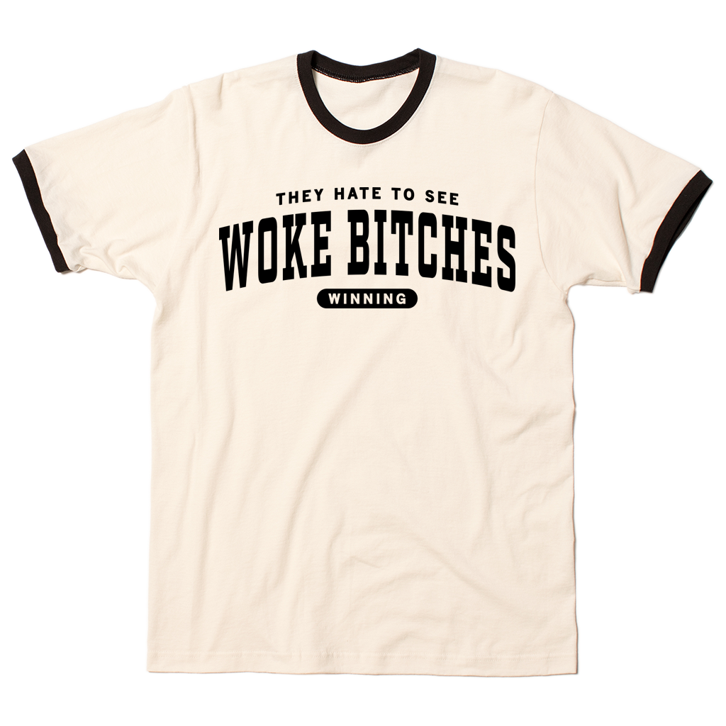 Ringer t-shirt with a cream base, black collar, and black around the sleeves. Centered black ink text says, "A folded heather grey t-shirt with black ink text that reads "They hate to see woke bitches winning"