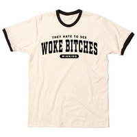 Ringer t-shirt with a cream base, black collar, and black around the sleeves. Centered black ink text says, "A folded heather grey t-shirt with black ink text that reads "They hate to see woke bitches winning"