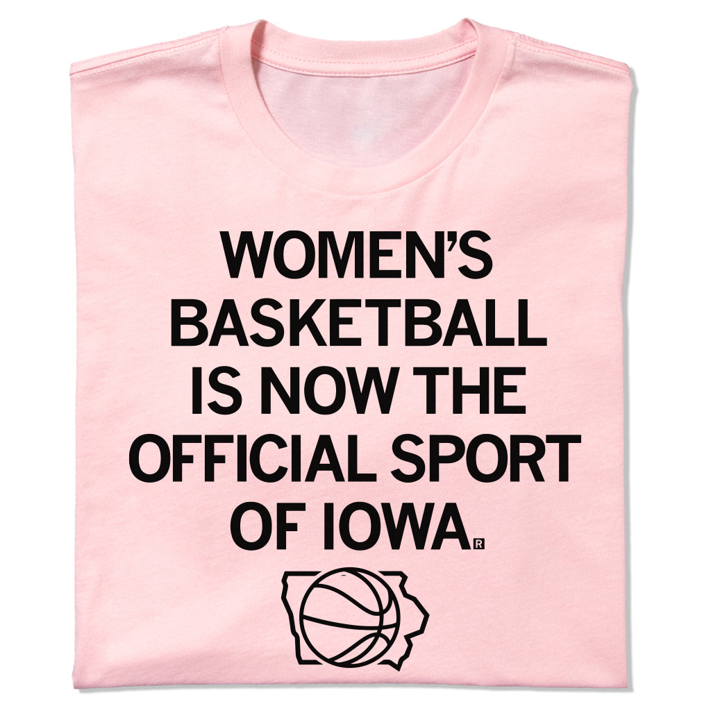 Light pink women’s basketball t-shirt featuring the text WOMENS BASKETBALL IS NOW THE OFFICIAL SPORT OF IOWA above a basketball silhouette inside an outline of the state of Iowa.