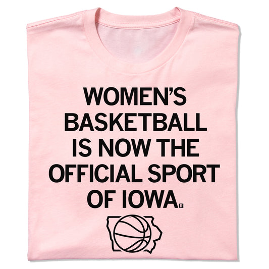 Light pink women’s basketball t-shirt featuring the text WOMENS BASKETBALL IS NOW THE OFFICIAL SPORT OF IOWA above a basketball silhouette inside an outline of the state of Iowa.