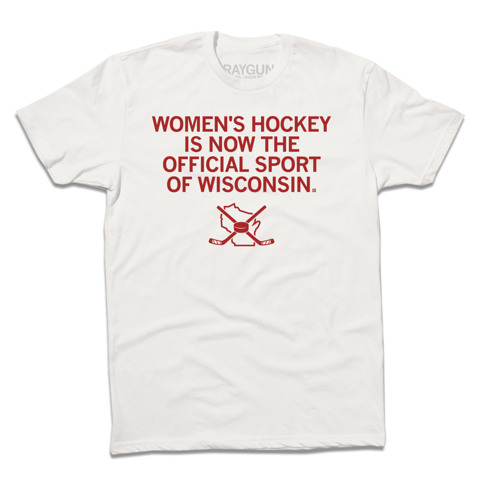 A dull white shirt with centered red in text that reads "Women's Hockey is now the Official Sport of Wisconsin" over an outline of Wisconsin with crossed hockey sticked and a puck centered on top of it.