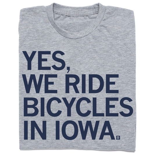 Folded heather grey t-shirt with left-aligned navy ink that says, "YES, WE RIDE BICYCLES IN IOWA."