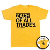Short-sleeve heather gold t-shirt with left-aligned black text that says, "ZACH OF ALL TRADES" with "ZACH LUTMER" in smaller text below. To the right of his name is an outline of Iowa with the number "6" in its center. A circular picture to the bottom right shows the back of the shirt. The back is printed like a jersey with "LUTMER" above a large 6.