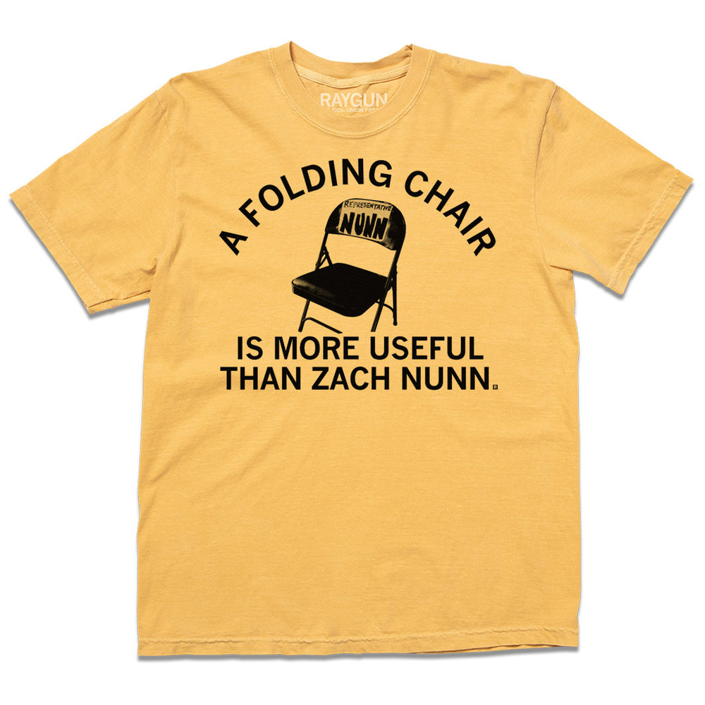 A laid flat mustard gold shirt with the text "a folding chair is more useful than Zach Nunn" in black ink around the illustration of a folding chair
