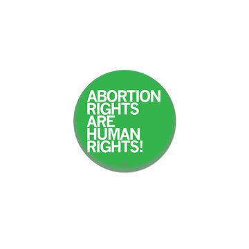 A round green metal button that reads, ABORTION RIGHTS ARE HUMAN RIGHTS!.