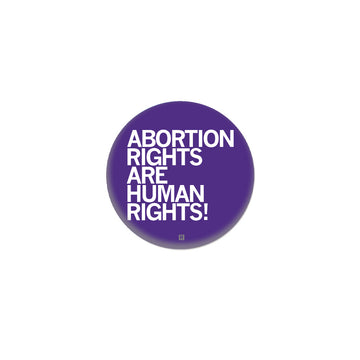 A round purple metal button with white text that reads, ABORTION RIGHTS ARE HUMAN RIGHTS!.