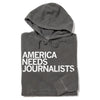 A charcoal gray Pigment Black Pullover Hoodie with the words AMERICA NEEDS JOURNALISTS printed in white on the front.