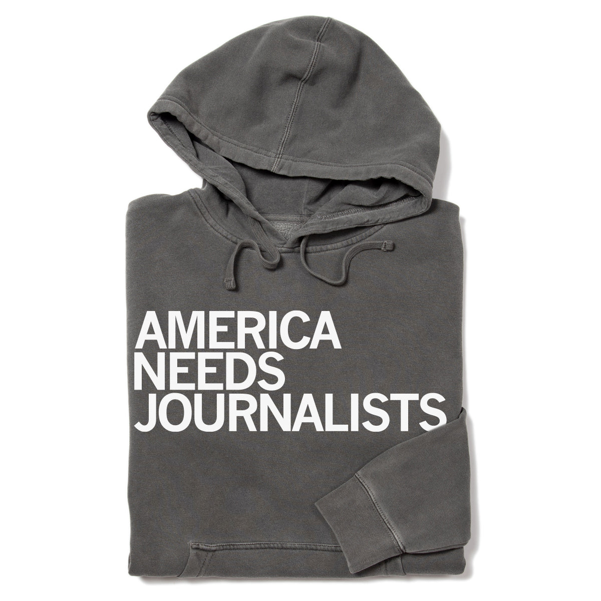 A charcoal gray Pigment Black Pullover Hoodie with the words AMERICA NEEDS JOURNALISTS printed in white on the front.