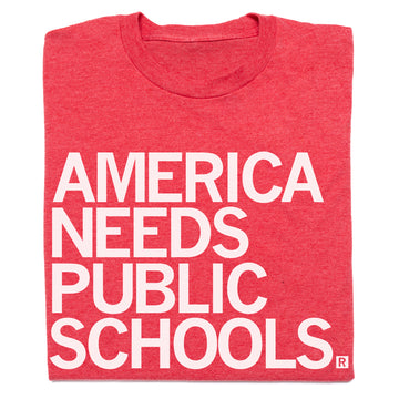 Folded red t-shirt with white text 'AMERICA NEEDS PUBLIC SCHOOLS' on a white background