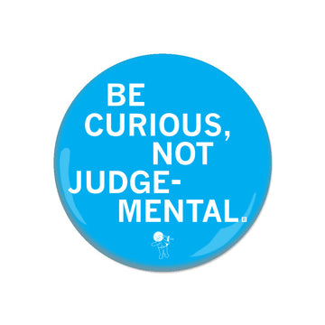 Bright blue RAYGUN metal button that reads, BE CURIOUS, NOT JUDGEMENTAL, with a small illustration of a cartoon astronaut at the bottom.