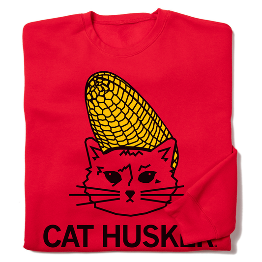 Red RAYGUN crew sweatshirt with a graphic of a cat wearing a corn cob on its head and the text CAT HUSKLER printed below.