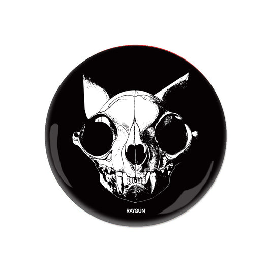 A circular RAYGUN metal button featuring a white line-art illustration of a cat skull on a black background.