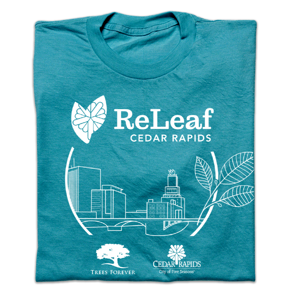 A folded teal t-shirt with white ink print depicting the Cedar Rapids skyline with text above that says, "ReLeaf Cedar Rapids" and below with the Trees forever logo and Cedar Rapids City of Five Seasons logo.