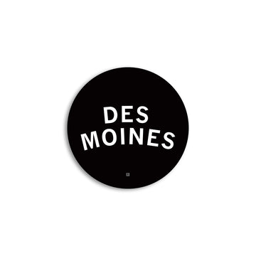 Black circular Des Moines logo with the words in white sans-serif capital letters on a vinyl sticker.