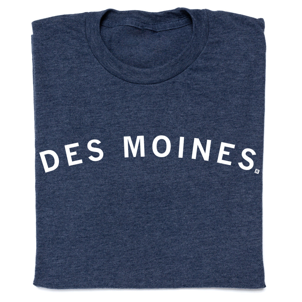 A folded navy blue RAYGUN T-shirt with the text DES MOINES printed in white across the chest.