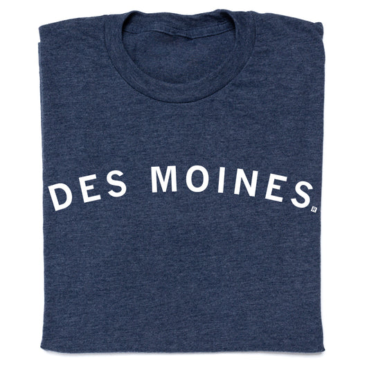A folded navy blue RAYGUN T-shirt with the text DES MOINES printed in white across the chest.