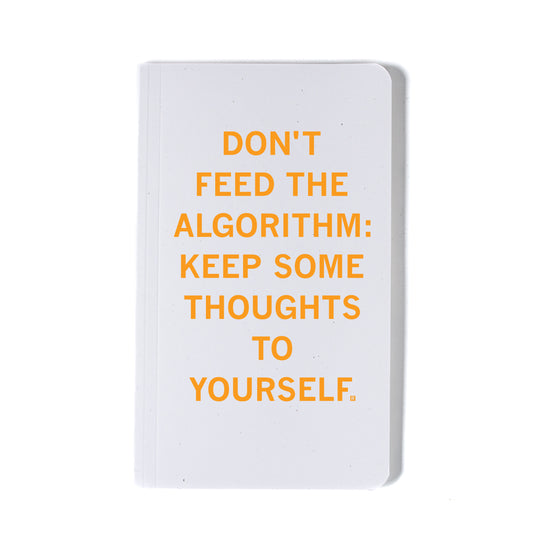 A white RAYGUN notebook with the orange text, DONT FEED THE ALGORITHM: KEEP SOME THOUGHTS TO YOURSELF.
