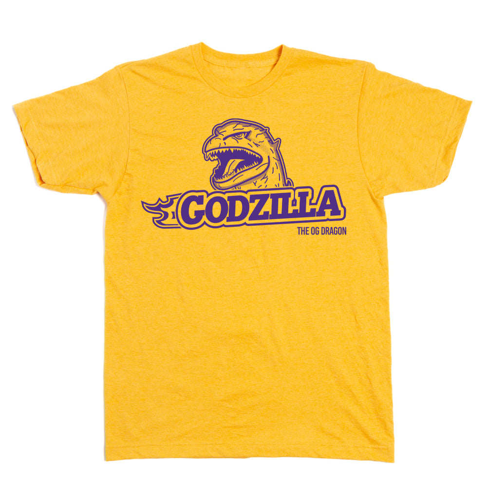 A heather mellow yellow t-shirt with purple ink that says, "Godzilla The OG Dragon" with Godzilla's head emerging above the text.