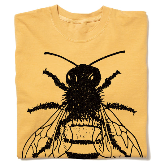 A folded mustard t-shirt in heavyweight cotton featuring a large black graphic of a bee.