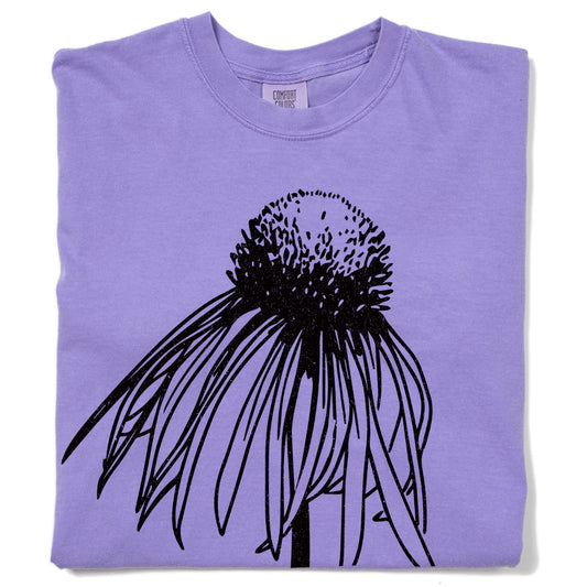 Folded pale purple t-shirt featuring a black line drawing of a coneflower.