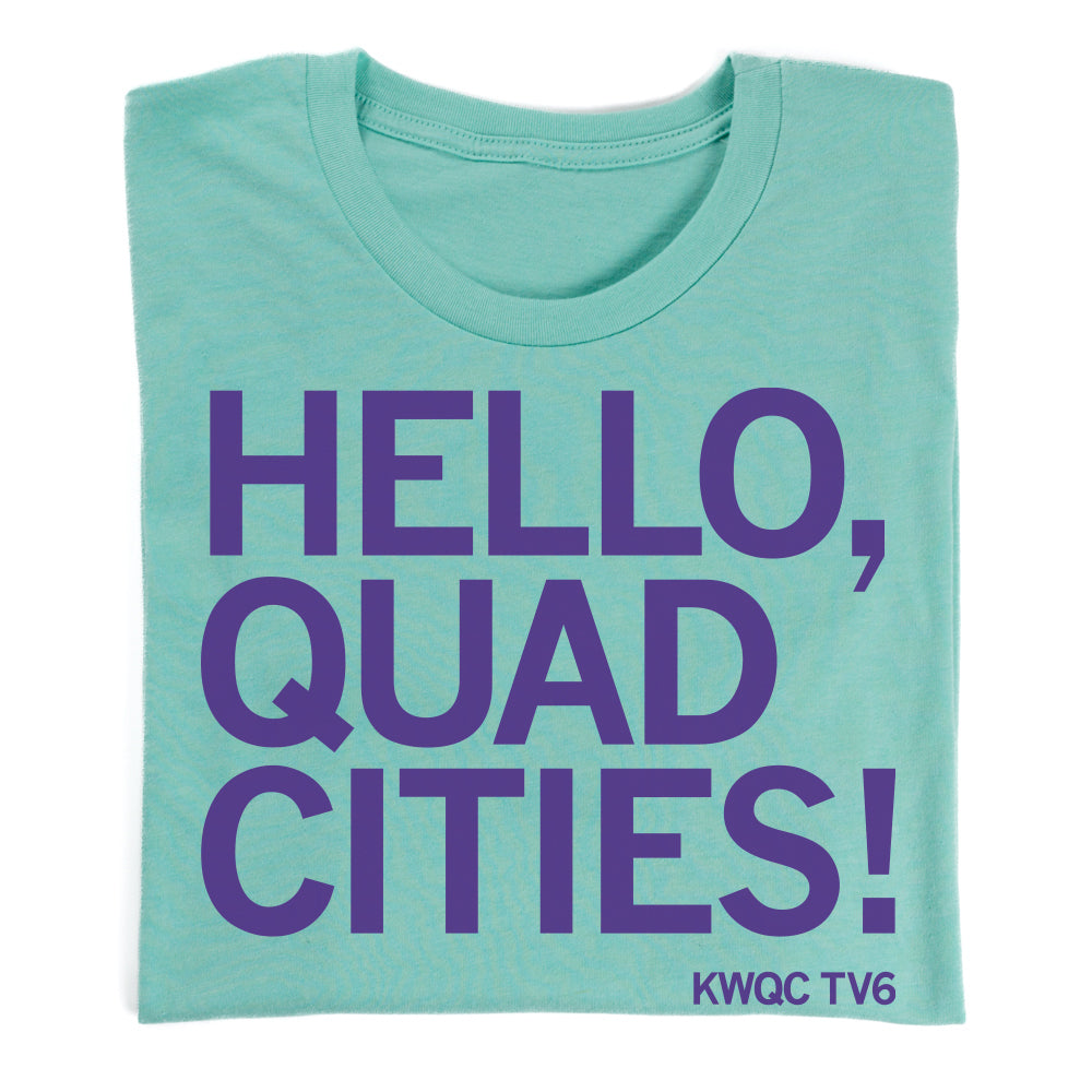A teal Paula Sands Live t-shirt featuring the purple text HELLO, QUAD CITIES! with KWQC TV6 printed in the bottom right corner.