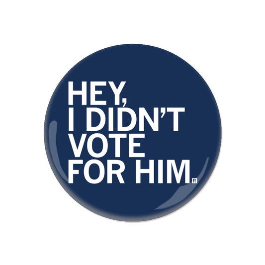 A navy blue circular RAYGUN metal button with white text that reads, HEY, I DIDNT VOTE FOR HIM.