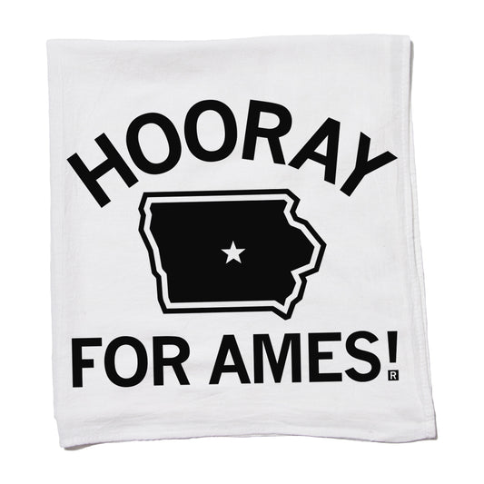 White RAYGUN flour sack towel featuring the black text HOORAY FOR AMES! above and below a black silhouette of the state of Iowa with a white star in the center.
