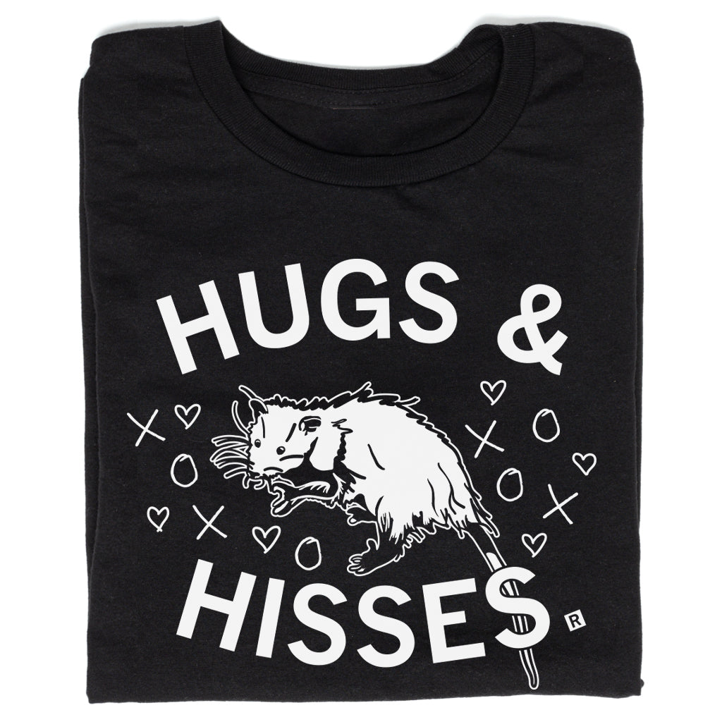 Union made black t-shirt featuring an illustration of an opossum surrounded by hearts, Xs, and Os, with the text HUGS & HISSES.