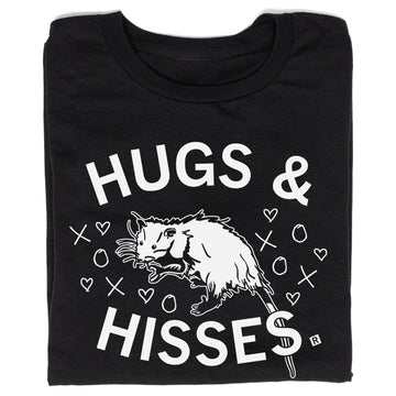Union made black t-shirt featuring an illustration of an opossum surrounded by hearts, Xs, and Os, with the text HUGS & HISSES.