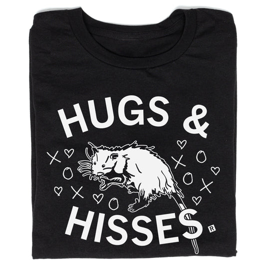 Union made black t-shirt featuring an illustration of an opossum surrounded by hearts, Xs, and Os, with the text HUGS & HISSES.