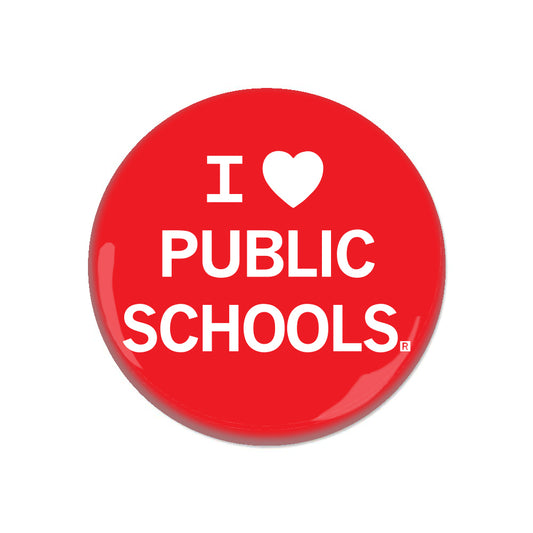 A red RAYGUN metal pin-back button with white text that reads I (heart symbol) PUBLIC SCHOOLS.