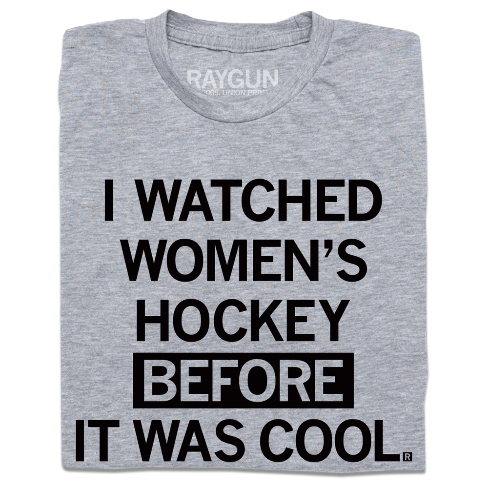A folded heather grey t-shirt with centered black in text that reads "I Watched Women's Hockey Before It Was Cool"