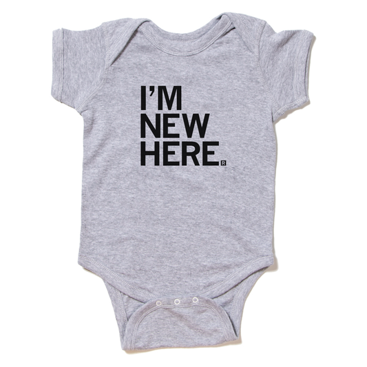 Gray baby onesie with the text IM NEW HERE. printed in black.