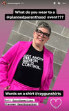 A person with short, gray hair and black-framed glasses wears a bright pink suit over a union-made black t-shirt that says, JUST ANOTHER SLUT ON BIRTH CONTROL.