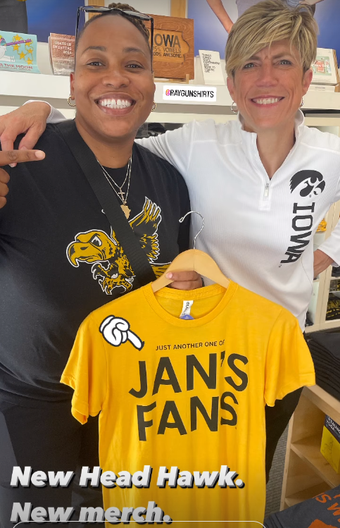 Two women smiling and holding up a union made Heather mellow yellow t-shirt that reads Just another one of Jans fans.