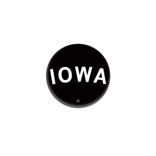 A black circular RAYGUN metal button featuring the word IOWA in white capital letters.