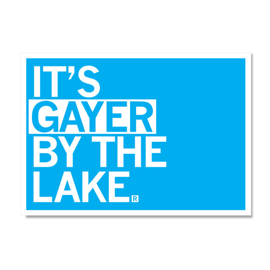 A blue rectangular RAYGUN postcard with white text that reads ITS GAYER BY THE LAKE.
