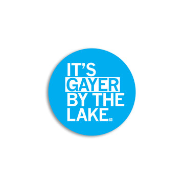 A blue circular RAYGUN vinyl sticker with white text that reads ITS GAYER BY THE LAKE.