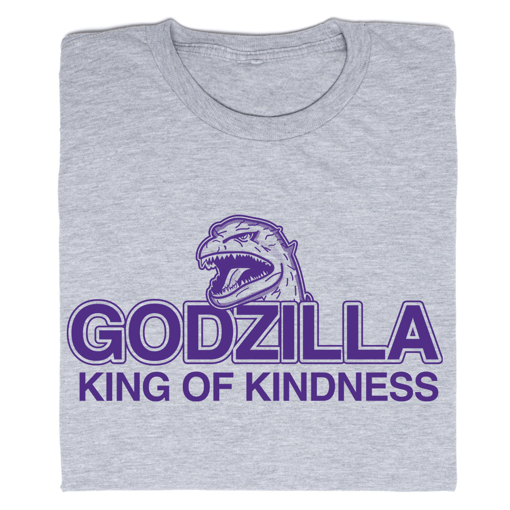 A folded heather grey t-shirt with purple ink that says, "Godzilla King of Kindness" with Godzilla's head emerging above the text.