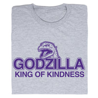 A folded heather grey t-shirt with purple ink that says, "Godzilla King of Kindness" with Godzilla's head emerging above the text.